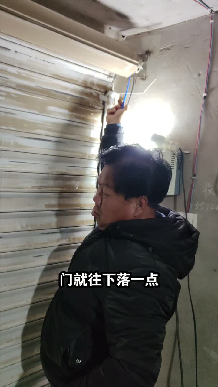 师傅小幅调节卷帘门下限位并观察门体下降位置